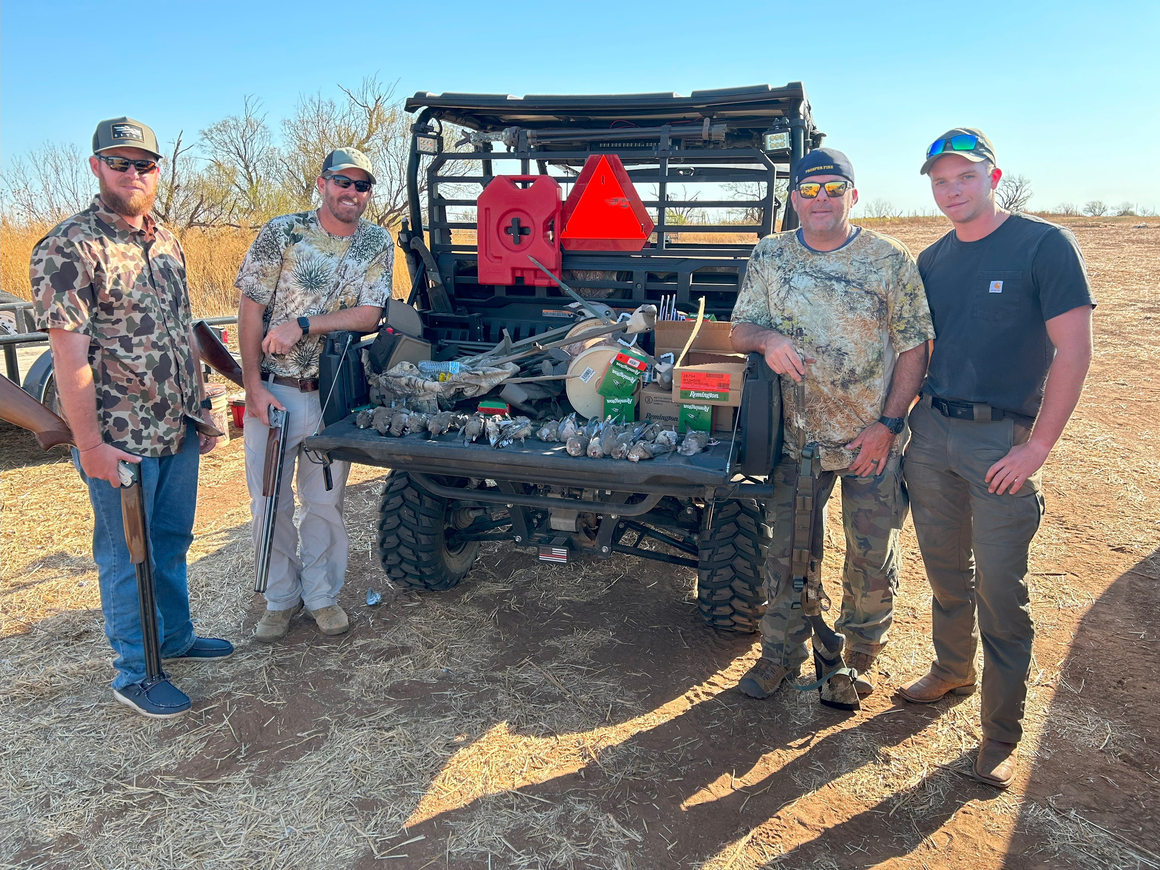 4 guys standing behind a UTV